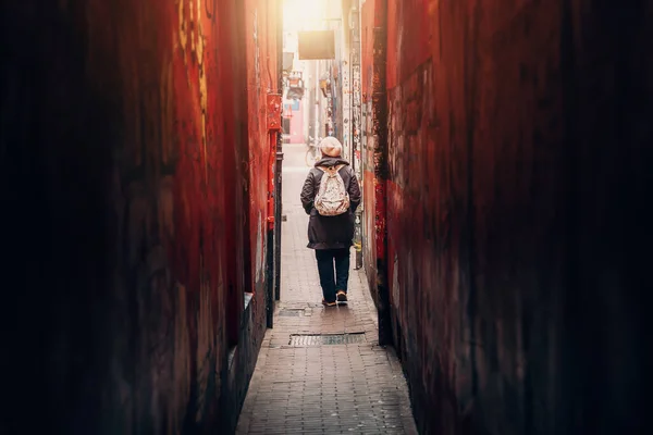 旅行者の女の子は、街の通り、リアビューの狭い長い赤い廊下やトンネルの葉 — ストック写真