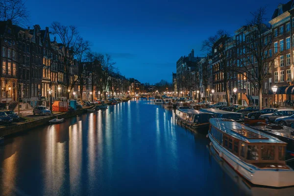 Amsterdam noche horizonte de la ciudad en el canal de agua frente al mar con casas de barcos, Amsterdam, Países Bajos — Foto de Stock