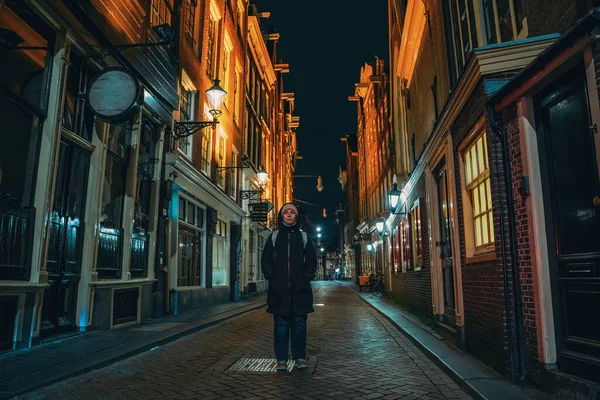 コロナウイルスcovid-19のために閉鎖されたレストラン、カフェ、店を持つ空の夜のアムステルダム通りの若い女性 — ストック写真