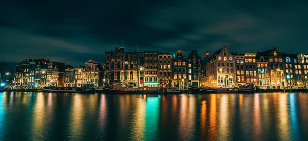 Amsterdam City panorama, osvětlené budovy nebo taneční domy s odrazem ve vodním kanálu v noci, Nizozemsko — Stock fotografie