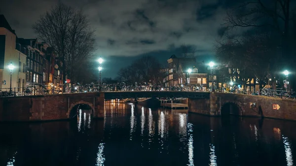 Canal con puente en iluminación nocturna con nubes, Amsterdam, Países Bajos — Foto de Stock