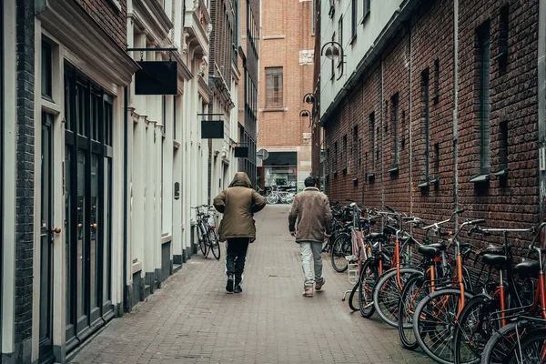 Coronavirus Covid-19 salgını nedeniyle kapalı barlar, restoranlar ve mağazalarla dolu boş bir Amsterdam caddesine giden iki adam karantina süresi — Stok fotoğraf