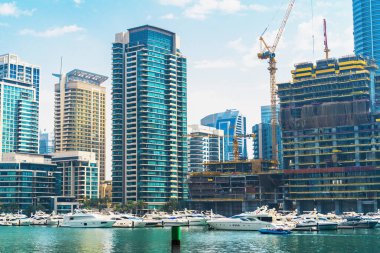 Dubai 'de hızlı gelişme. Dubai Marina 'da lüks yatları ve tekneleri olan sanayi vinçleri olan yüksek binalar ve şantiyeler.