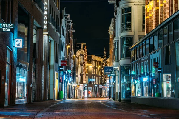 Amsterdam, Nizozemsko - 18. března 2020: Prázdná nákupní ulice bez lidí s uzavřenými obchody ve večerních hodinách v turistickém centru Amsterdamu, město v karanténě z Coronaviru — Stock fotografie