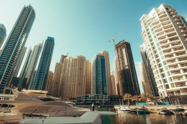 Dubai Marina gökdelenleri arka planda ve su kanalı Dubai, Birleşik Arap Emirlikleri 'nde tekneleri olan lüks bir yatta.
