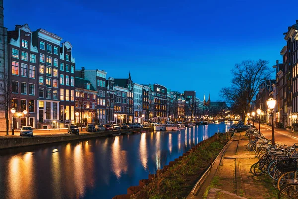 Amsterdam canal con típicas casas de baile holandés por la noche con reflexiones de luces de la ciudad en el agua, Holanda, Países Bajos — Foto de Stock
