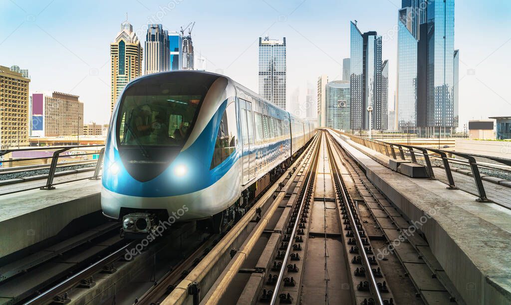 Dubai metro train on rails at background of skyscrapers. Famous outdoor subway Red Line