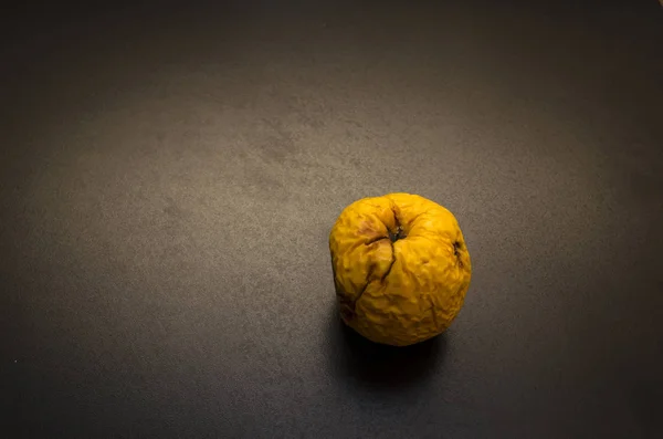 Yellow rotten apple with hole on dark background, or wrinkled apple — Stock Photo, Image