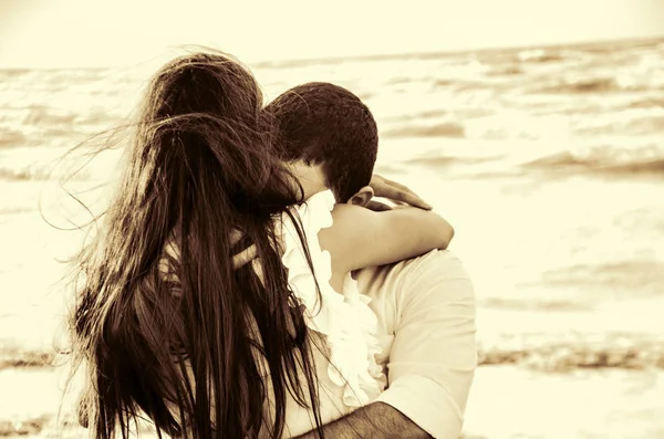 Feliz abrazo pareja en la playa con el mar borroso en el fondo o pareja encantadora en seaside.Love, felicidad, escena romántica . — Foto de Stock
