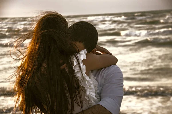 Lykkelig klemmende par på stranden med tåkete hav på bakgrunn eller nydelig par på sjøen. Kjærlighet, lykke, romantisk scene. . – stockfoto