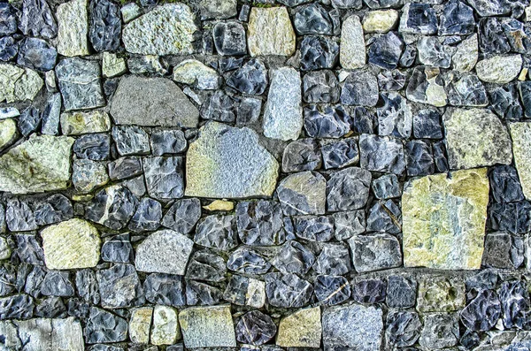 Fragmento de pared de ladrillo viejo con piedras de río textura blanco gris marrón negro verde azul lima amarillo naranja granate violeta rosa turquesa de color de fondo, diferentes tipos de piedras superficie del mosaico — Foto de Stock