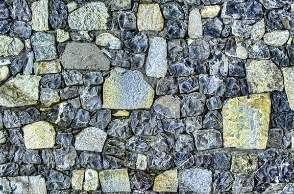 Fragment de vieux mur de briques avec des pierres de rivière texture blanc gris brun noir vert bleu citron vert jaune orange marron violet rose turquoise fond de couleur, différents types de pierres surface de la mosaïque — Photo