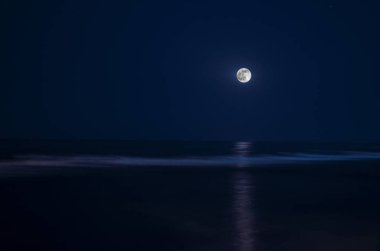 Ay ışığının aydınlattığı su üzerinde gece gökyüzünde dolunay