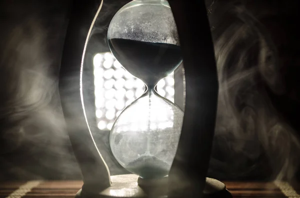 Time concept. Silhouette of Hourglass clock and smoke on dark background with hot yellow orange red blue cold back lighting, or symbols of time with copy space, sandglass or sand clock — Stock Photo, Image