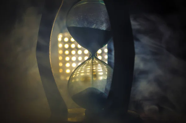 Concept du temps. Silhouette d'horloge sablier et fumée sur fond sombre avec éclairage arrière chaud jaune orange rouge bleu froid, ou symboles du temps avec espace de copie, sablier ou horloge de sable — Photo