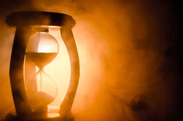 Tijd concept. Silhouet van zandloper klok en rook op donkere achtergrond met warm geel oranje rood blauw koude tegenlicht of symbolen van tijd met de ruimte, sandglass of zand klok kopie — Stockfoto