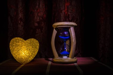 Sevgililer günü kompozisyon koyu arka plan ve kum siluet saat, zaman ve aşk kavramı, seçici odak veya sevgi tebrik kartı kalp kırmızı yeşil renkli kalp yanan sweet ile