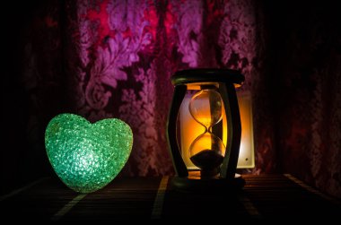 Sevgililer günü kompozisyon koyu arka plan ve kum siluet saat, zaman ve aşk kavramı, seçici odak veya sevgi tebrik kartı kalp kırmızı yeşil renkli kalp yanan sweet ile