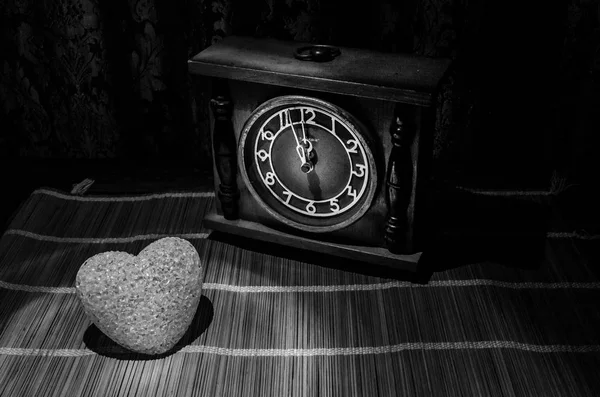 Valentine\'s Day composition with sweet burning multicolored heart on dark background and old vintage clock, time and love concept, selective focus, or love greeting card of heart red green pink yellow
