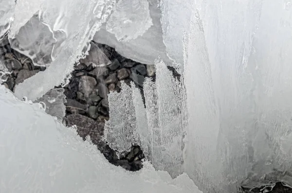 Vista esterna di blocchi di ghiaccio in acqua ghiacciata in struttura invernale con neve bianca leggera che copre pezzi di ghiaccio incrinato su un terreno invernale ghiacciato — Foto Stock