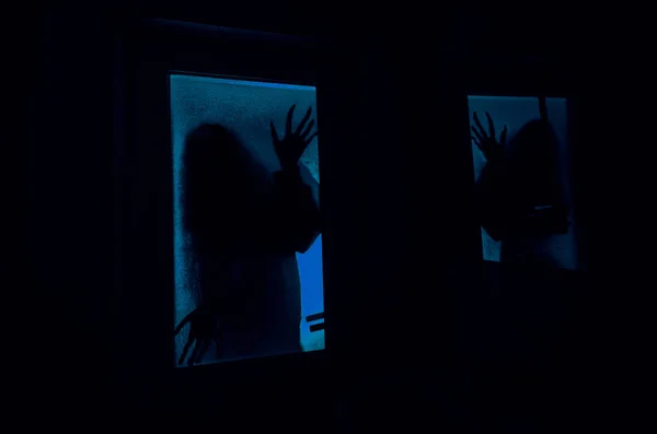 Horror woman in window wood hand hold cage scary scene halloween concept Blurred silhouette of witch