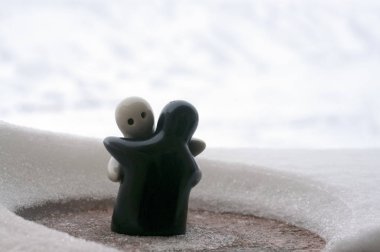 Aşk Sevgililer günü kavramı buz eriyor. F kız ve bir erkek bebek hugs her diğer, arka plan bulanık ile beyaz kar tutuyoruz. Heykeller sarılma. Hatıra. Mermer nesne. Seviyorum. Sempati