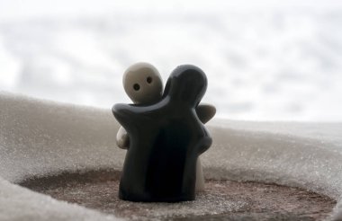 Aşk Sevgililer günü kavramı buz eriyor. F kız ve bir erkek bebek hugs her diğer, arka plan bulanık ile beyaz kar tutuyoruz. Heykeller sarılma. Hatıra. Mermer nesne. Seviyorum. Sempati