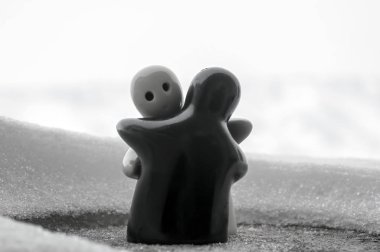 Aşk Sevgililer günü kavramı buz eriyor. F kız ve bir erkek bebek hugs her diğer, arka plan bulanık ile beyaz kar tutuyoruz. Heykeller sarılma. Hatıra. Mermer nesne. Seviyorum. Sempati