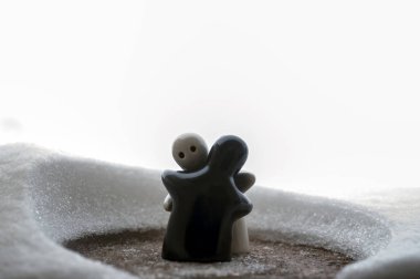 Aşk Sevgililer günü kavramı buz eriyor. F kız ve bir erkek bebek hugs her diğer, arka plan bulanık ile beyaz kar tutuyoruz. Heykeller sarılma. Hatıra. Mermer nesne. Seviyorum. Sempati