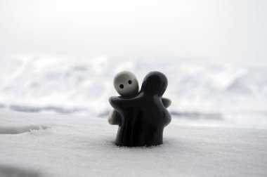 Aşk Sevgililer günü kavramı buz eriyor. F kız ve bir erkek bebek hugs her diğer, arka plan bulanık ile beyaz kar tutuyoruz. Heykeller sarılma. Hatıra. Mermer nesne. Seviyorum. Sempati