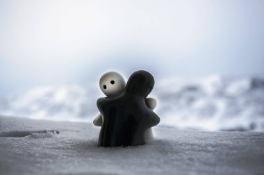 Aşk Sevgililer günü kavramı buz eriyor. F kız ve bir erkek bebek hugs her diğer, arka plan bulanık ile beyaz kar tutuyoruz. Heykeller sarılma. Hatıra. Mermer nesne. Seviyorum. Sempati