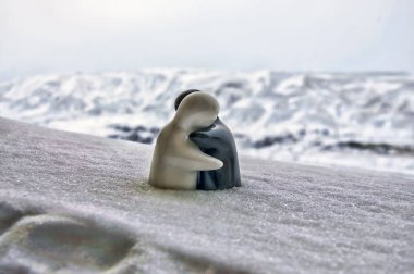 Aşk Sevgililer günü kavramı buz eriyor. F kız ve bir erkek bebek hugs her diğer, arka plan bulanık ile beyaz kar tutuyoruz. Heykeller sarılma. Hatıra. Mermer nesne. Seviyorum. Sempati