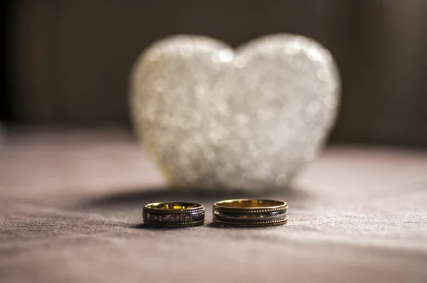 Kärlek, bröllop och alla hjärtans dag koncept. Vackra gyllene vigselringar och glas hjärta selektivt fokus. användbar som gratulationskort — Stockfoto