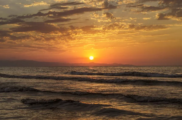 Hermoso paisaje de puesta de sol ardiente en el mar Caspio y el cielo naranja por encima de ella con impresionante reflejo dorado sol en las olas tranquilas como fondo. Increíble vista al atardecer de verano en la playa. Azerbaiyán naturaleza , — Foto de Stock