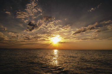 Hazar Denizi ve arka plan olarak sakin dalgalar üzerinde harika güneş altın yansıması ile üstündeki turuncu gökyüzü günbatımı manzara yanan güzel. Sahilde muhteşem gün batımı görünümü. Azerbaycan Abşeron, Bakü