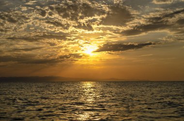 Hazar Denizi ve arka plan olarak sakin dalgalar üzerinde harika güneş altın yansıması ile üstündeki turuncu gökyüzü günbatımı manzara yanan güzel. Sahilde muhteşem gün batımı görünümü. Azerbaycan Abşeron, Bakü