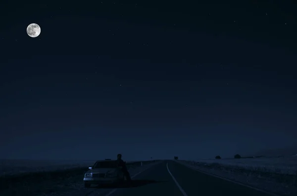 車と人間の sillhouette 月の光の下で夜に道路側の車と道路。アゼルバイジャン イワノフカ — ストック写真