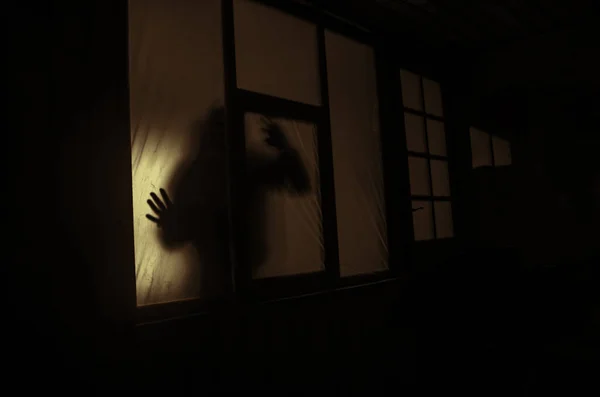 Korku kavramı. Bir pencerenin önünde püskürtülür kolları olan bir insan silüeti. Geceleyin. — Stok fotoğraf