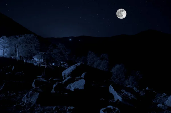 Прекрасний нічний вид на яскравий чарівний Місяць з темно-синіми хмарами під пагорбами — стокове фото