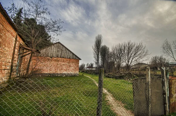 Straße in Dorf in winterlicher Landschaft die Abendsonne. atmosphärischer ländlicher Moment. altes Haus an der Straße mit Bäumen am Gazakh Azerbaijan — Stockfoto