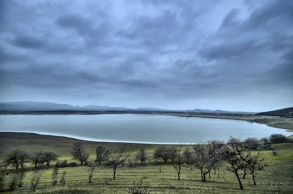 Bellissimo paesaggio invernale di lago e montagne e alberi. Acqua ferma del lago con drammatico fondale montano Latrigg in Azerbaigian. Caucaso Gazakh — Foto Stock