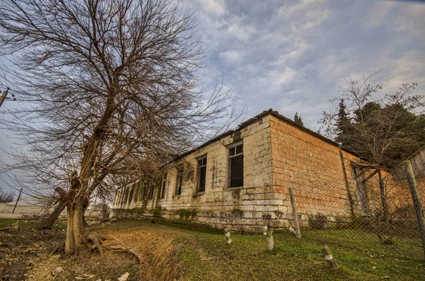 Strada di terra nel villaggio nella campagna invernale la luce del sole di sera. momento rurale atmosferico. Vecchia casa sulla strada con alberi a Gazakh Azerbaijan — Foto Stock