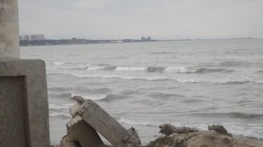 Deniz dalgaları kazasında kaya karşı Hazar denizin dalgaları bulutlu hava sahilde kayalık ve eski metalik inşaatı çökmesini. Azerbaycan Abşeron Novkhani