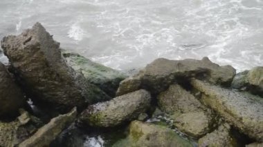 Deniz dalgaları kazasında kaya karşı Hazar denizin dalgaları bulutlu hava sahilde kayalık ve eski metalik inşaatı çökmesini. Azerbaycan Abşeron Novkhani