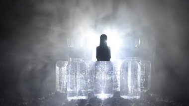 Vape kavramı. Duman bulutları ve vape sıvı şişe koyu arka plan üzerinde. Işık efektleri. Arka plan veya vape reklam olarak yararlı.