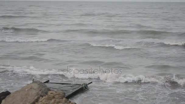 Olas del mar chocan contra la roca, las olas del mar Caspio se están estrellando en una construcción rocosa y metálica de edad en la playa tiempo nublado. Azerbaiyán Absheron Novkhani — Vídeo de stock