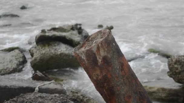 Olas del mar chocan contra la roca, las olas del mar Caspio se están estrellando en una construcción rocosa y metálica de edad en la playa tiempo nublado. Azerbaiyán Absheron Novkhani — Vídeo de stock