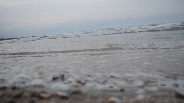 Le onde del Mar Caspio sono arrotolate su una spiaggia di sabbia e conchiglie con una pietra di granito giallo. Concentrazione selettiva sul tempo nuvoloso. Absheron Azerbaigian — Video Stock