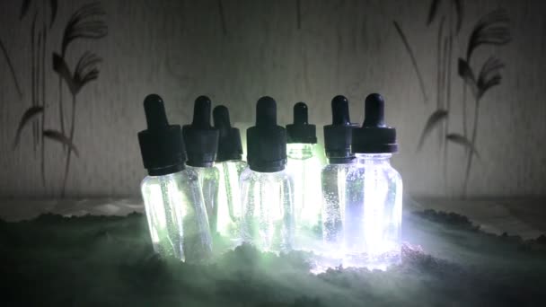 Vape concept. Roken wolken en vape vloeibare flessen op donkere achtergrond. Lichteffecten. Nuttig als achtergrond of vape advertentie. — Stockvideo