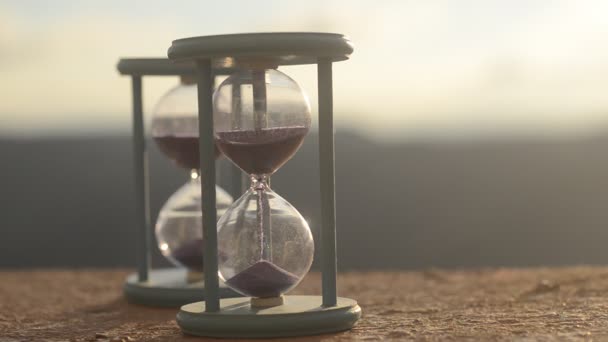 Concepto de tiempo. Silueta de reloj de arena y humo en el fondo borroso de la naturaleza al atardecer, o símbolos del tiempo bajo el humo, el tiempo termina o el amor termina. Ideas optimistas o pesimistas . — Vídeos de Stock